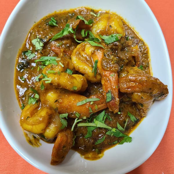 Shaad Deshi Cuisine's Indian shrimp curry, garnished with fresh cilantro, in a white bowl.
