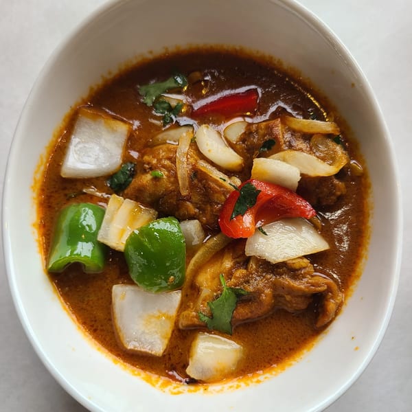 Shaad Deshi Cuisine's Indian curry with chicken, onions, green and red bell peppers in a white bowl.